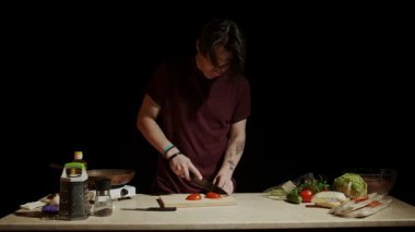 Bir insan, rahat bir mutfak ortamında ahşap bir tahtada ustalıkla taze sebzeleri kesiyor. Yavaş çekim