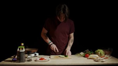 Mutfakta bir şef, tezgahta taze malzemelerle çevrili salatalık pişirmek için ustalıkla salatalık doğruyor. Yavaş çekim