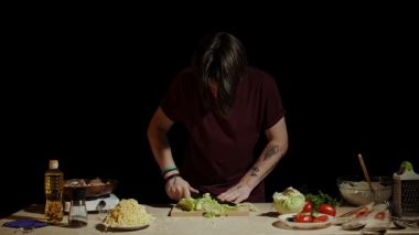 Bir şef salata hazırlamak için taze sebze kesiyor. İçindekiler arasında marul, domates ve daha fazlası var. Yavaş çekim