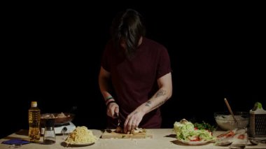 Şef yemek için malzemeleri hazırlar, etraftaki çeşitli malzemeler arasında bir kesim tahtasındaki mantarları ustalıkla dilimler. Yavaş çekim