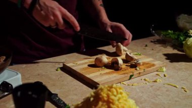 Bir şef ahşap bir tahtada mantar doğruyor, ev yapımı yemek pişirmek için taze malzemeler hazırlıyor..