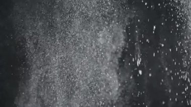 Dumanlı havada rastgele uçan küçük toz bulutu, nesneler için boş uzay şablonu. Birçok toz parçacığı beyaz toz aşağı akıyor, boş siyah kontrast arka planda yüzüyor. Yavaş çekim.