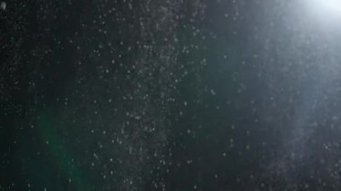 Dumanlı havada rastgele uçan küçük toz bulutu, nesneler için boş uzay şablonu. Bir çok toz parçacığı, spot ışıklarıyla boş bir siyah kontrast arka planına düşüyor. Yavaş çekim.