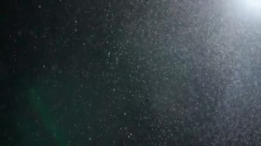 Dumanlı havada rastgele uçan küçük toz bulutu, nesneler için boş uzay şablonu. Birçok toz parçacığı yukarıdan düşüyor, spot ışıklarının altında boş siyah bir zemin üzerinde yüzüyor. Yavaş çekim.