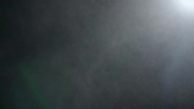 Dumanlı havada rastgele uçan küçük toz bulutu, nesneler için boş uzay şablonu. Birçok toz parçacığı beyaz toz spot ışıklarıyla boş siyah arkaplan üzerinde yüzüyor. Yavaş çekim.