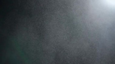 Dumanlı havada rastgele uçan küçük toz bulutu, nesneler için boş uzay şablonu. Birçok toz parçacığı beyaz toz spot ışıkları altında boş siyah kontrast arka planda yüzüyor. Yavaş çekim.