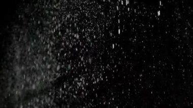 Dumanlı havada rastgele uçan küçük toz bulutu, nesneler için boş uzay şablonu. Yukarıdan bir sürü toz beyaz parçacığı düşüyor, boş siyah arka planda yüzüyor. Yavaş çekim.