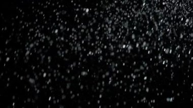 Dumanlı havada rastgele uçan küçük toz bulutu, nesneler için boş uzay şablonu. Yukarıdan düşen gümüş parçacıkları boş siyah zıtlık arka planında yüzüyor. Yavaş çekim.
