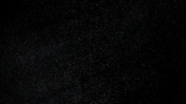 Dumanlı havada rastgele uçan küçük toz bulutu, nesneler için boş uzay şablonu. Birçok toz parçacığı, karanlıkta boş siyah zıtlık zemininde yüzüyor. Yavaş çekim.