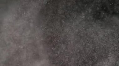Dumanlı havada rastgele uçan küçük toz bulutu, nesneler için boş uzay şablonu. Büyük bulutlarda beyaz toz parçacıkları boş siyah kontrastlı arka planda ışık altında yüzüyor.