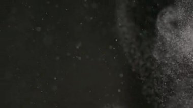 Dumanlı havada rastgele uçan küçük toz bulutu, nesneler için boş uzay şablonu. Beyaz toz bulutundaki pek çok toz parçacığı boş siyah karşıtlık arkaplanındaki ışıkta tepeden aşağıya süzülüyor.