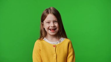 Çocuk duyguları reklam konsepti. Sarı tişörtlü küçük kız kameraya bakıyor, gülümsüyor, krom anahtar yeşil ekranda izole edilmiş arka plan modeli..