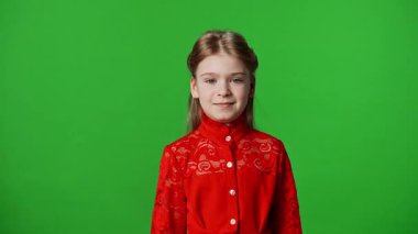 Çocuk duyguları reklam konsepti. Kırmızı tişörtlü küçük kız kameraya bakıyor ve gülümsüyor. Renkli anahtar yeşil ekran arka plan modelinde izole edilmiş..