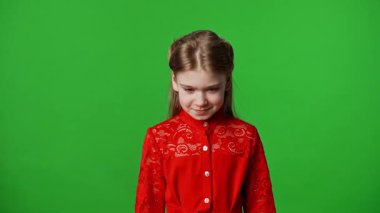Çocuk duyguları reklam konsepti. Kırmızı tişörtlü küçük kız başını kaldırır ve kameraya bakar, gülümser yüz ifadesi, krom anahtar yeşil ekranda izole edilmiş arka plan modeli..
