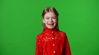 Çocuk duyguları reklam konsepti. Kırmızı tişörtlü küçük kız kameraya bakıyor ve gülüyor, pozitif ifade, krom anahtar yeşil ekranda izole edilmiş arka plan modeli..