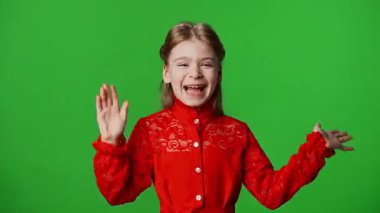 Çocuk duyguları reklam konsepti. Gülümseyen kız heyecanla el sallıyor ve gülüyor ve yüzünü tutuyor, olumlu ifade, krom anahtar yeşil ekran arka plan modelinde izole edilmiş..