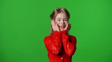 Çocuk duyguları reklam konsepti. Gülümseyen kız heyecanla gülüyor ve yüzünü tutuyor, pozitif ifade, krom anahtar yeşil ekranda izole edilmiş arka plan modeli..