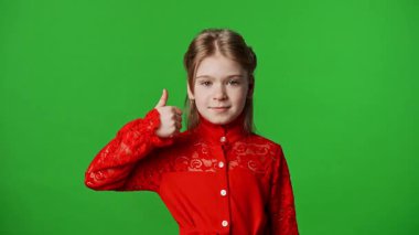 Çocuk duyguları reklam konsepti. Gülümseyen kız kameraya bakar ve el işaretini gösterir, olumlu ifade, krom anahtar yeşil ekran arka plan modelinde izole edilmiş.