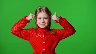 Çocuk duyguları reklam konsepti. Gülümseyen kız kameraya bakar ve el işaretlerini, olumlu ifadeyi gösterir. Krom anahtar yeşil ekran arka plan modelinde izole edilmiştir..
