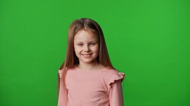 Çocuk duyguları reklam konsepti. Tişörtlü küçük kız kameraya bakıyor ve gülüyor, pozitif ifade, krom anahtar yeşil ekranda izole edilmiş arka plan modeli..