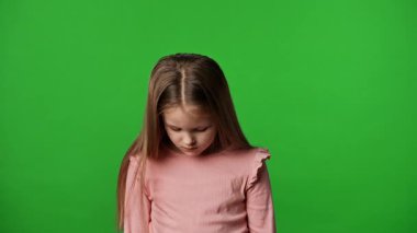 Çocuk duyguları reklam konsepti. Tişörtlü küçük kız başını kaldırıp kameraya bakıyor, gülümsüyor, krom anahtar yeşil ekran arka plan modelinde izole edilmiş..