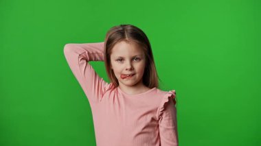 Çocuk duyguları reklam konsepti. Gülümseyen kız suratını ekşitiyor, komik suratlar yapıyor ve dili dışarı çıkıyor, pozitif ifade, krom anahtar yeşil ekran arka plan modelinde izole edilmiş..