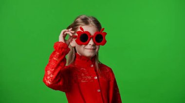 Çocuk duyguları reklam konsepti. Serin elma gözlüklü gülümseyen kız, pozlar ve gülümsemeler, pozitif ifade, krom anahtar yeşil ekran arka plan modelinde izole edilmiş..