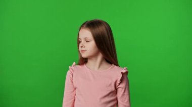 Çocuk duyguları reklam konsepti. Gülümseyen kız etrafa bakıyor ve kameraya el sallıyor, pozitif ifade, krom anahtar yeşil ekranda izole edilmiş arka plan modeli..