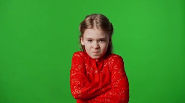 Çocuk duyguları reklam konsepti. Çapraz kollu ve kızgın yüzlü küçük kız kameraya bakıyor, negatif yüz ifadesi, krom anahtar yeşil ekranda izole edilmiş arka plan modeli..
