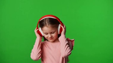 Çocuk duyguları reklam konsepti. Gülümseyen çocuk kulaklıkla müzik dinliyor ve dans ediyor, pozitif ifade, krom anahtar yeşil ekranda izole edilmiş arka plan modeli..