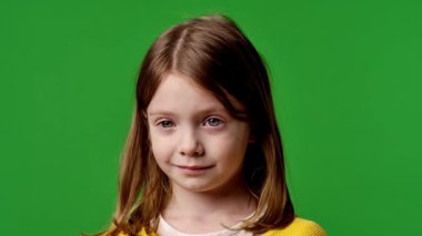 Çocuk duyguları reklam konsepti. Sarı tişörtlü küçük kız kameraya bakıyor, gülümsüyor, krom anahtar yeşil ekranda izole edilmiş arka plan modeli..