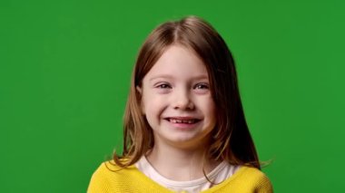 Çocuk duyguları reklam konsepti. Sarı tişörtlü küçük kız kameraya bakıyor, gülümsüyor, krom anahtar yeşil ekranda izole edilmiş arka plan modeli..