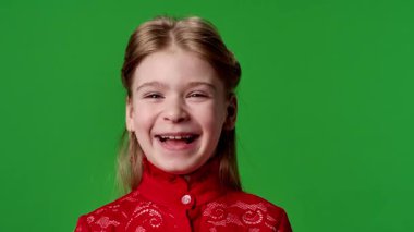 Çocuk duyguları reklam konsepti. Kırmızı tişörtlü küçük kız kameraya bakıyor ve gülüyor, pozitif ifade, krom anahtar yeşil ekranda izole edilmiş arka plan modeli..