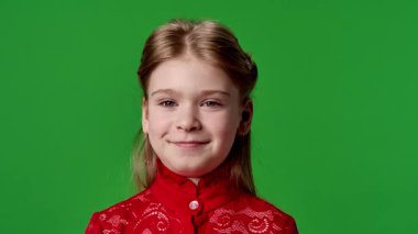 Çocuk duyguları reklam konsepti. Kırmızı tişörtlü küçük kız kameraya bakıyor ve gülümsüyor, pozitif ifade, krom anahtar yeşil ekranda izole edilmiş arka plan modeli..