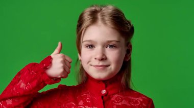 Çocuk duyguları reklam konsepti. Gülümseyen kız kameraya bakar ve el işaretini gösterir, olumlu ifade, krom anahtar yeşil ekran arka plan modelinde izole edilmiş.