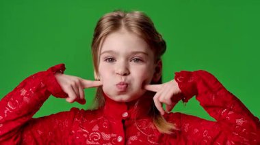 Çocuk duyguları reklam konsepti. Gülümseyen kız suratını ekşitiyor, komik suratlar yapıyor ve dili dışarı çıkıyor, pozitif ifade, krom anahtar yeşil ekran arka plan modelinde izole edilmiş..