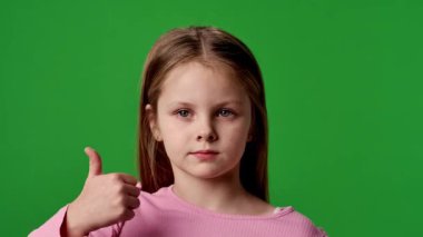 Çocuk duyguları reklam konsepti. Gülümseyen kız kameraya bakar ve el işaretini gösterir, olumlu ifade, krom anahtar yeşil ekran arka plan modelinde izole edilmiş.