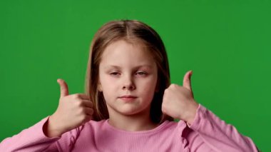 Çocuk duyguları reklam konsepti. Gülümseyen kız kameraya bakar ve el işaretlerini, olumlu ifadeyi gösterir. Krom anahtar yeşil ekran arka plan modelinde izole edilmiştir..