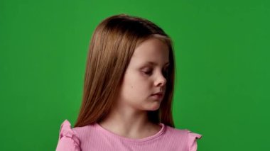Çocuk duyguları reklam konsepti. Gülümseyen kız etrafa bakıyor ve kameraya el sallıyor, pozitif ifade, krom anahtar yeşil ekranda izole edilmiş arka plan modeli..