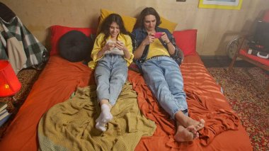 Bir çift renkli bir retro odasında rahat vakit geçirirken telefonlarıyla vakit geçiriyorlar..