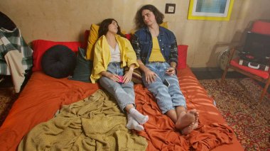 Bir çift renkli bir retro odasında rahat vakit geçirirken telefonlarıyla vakit geçiriyorlar..