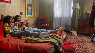 Bir çift renkli bir retro odasında rahat vakit geçirirken telefonlarıyla vakit geçiriyorlar..