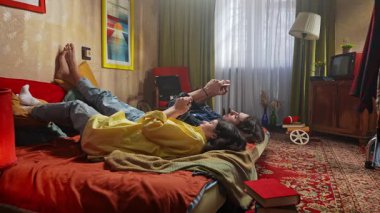 Bir çift renkli bir retro odasında rahat vakit geçirirken telefonlarıyla vakit geçiriyorlar..