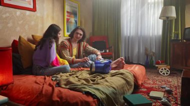 Genç bir kadın ve erkeğin eski bir kayıt cihazında müzik dinlediği canlı bir sahne..