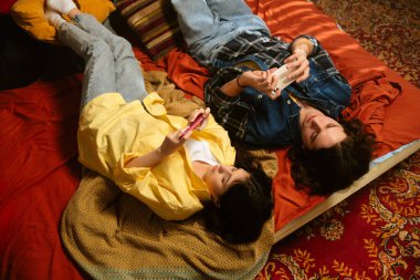 Bir çift renkli eski moda bir odada rahat bir anın tadını çıkarıyor. İçkilerini yudumluyor ve telefon kullanıyor. Üst çekim