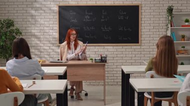 Bir öğretmen öğrencilere dil bilgisi zamanlarını anlamada rehberlik eder, örnekler sunar.