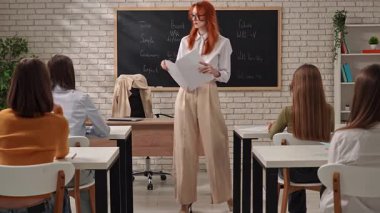 Bir öğretmen sınıfta dil bilgisi kurallarını tutkuyla anlatıyor, öğrencileri açık örneklerle meşgul ediyor.