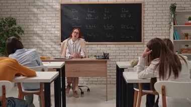 Bir öğretmen öğrencilere dil bilgisi zamanlarını anlamada rehberlik eder, örnekler sunar.