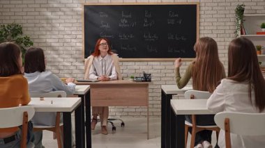 Bir öğretmen öğrencilere dil bilgisi zamanlarını anlamada rehberlik eder, örnekler sunar.