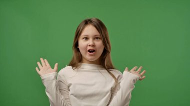 Gençlik duyguları konsepti. Kameraya poz veren genç kız el ele tutuşuyor. Şaşırtıcı, gülümseyen olumlu ifade. Krom anahtar yeşil ekran stüdyo arka planında izole edilmiş..